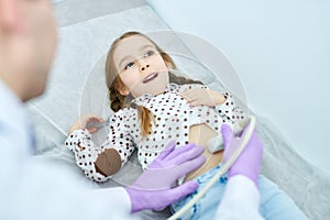 Medical specialistÃÂ checking up stomachÃÂ of cute girl photo